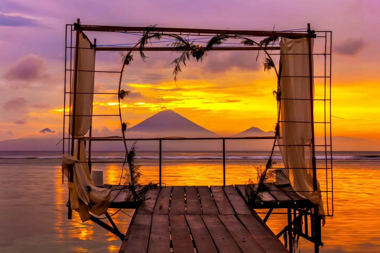 Sunset view of a mountain framed by a heart-shaped decoration on a wooden pier.