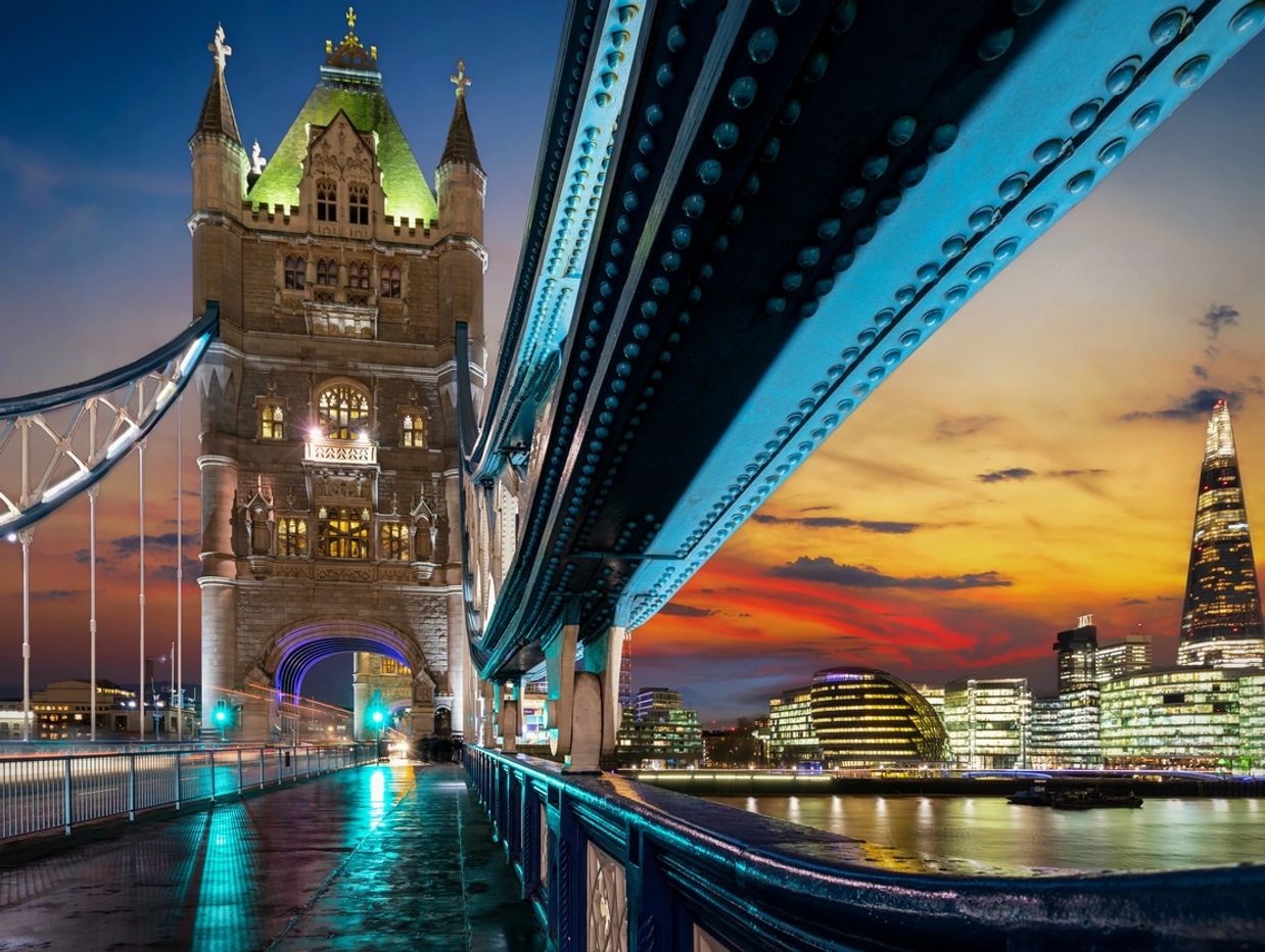 Tower Bridge in London illuminated at sunset with city lights reflecting on the water.