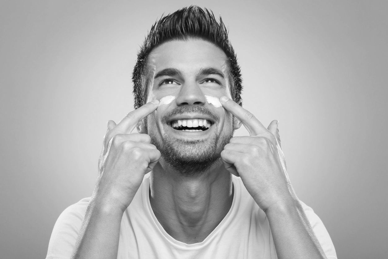 Smiling client touching his face after a skincare treatment.