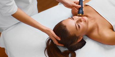 Woman receiving facial treatment with a device.