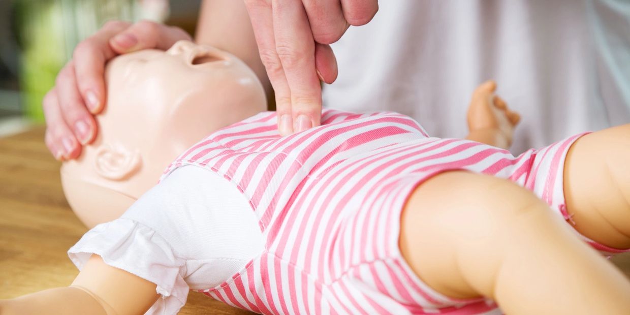 A person doing CPR on a baby manakin