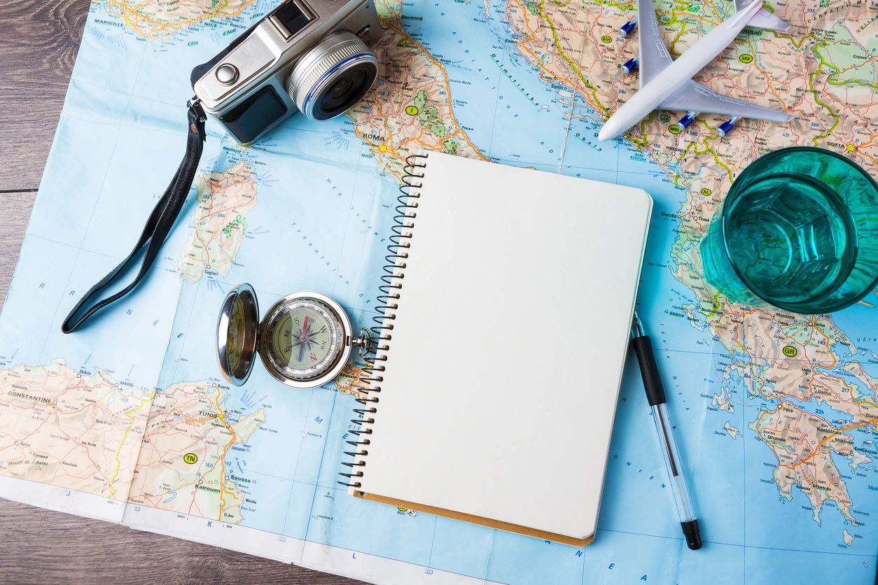 Journal on a map with a compass, camera, and airplane.