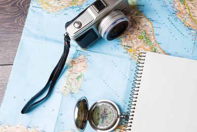 Camera, compass, and notebook on a map for travel planning.
