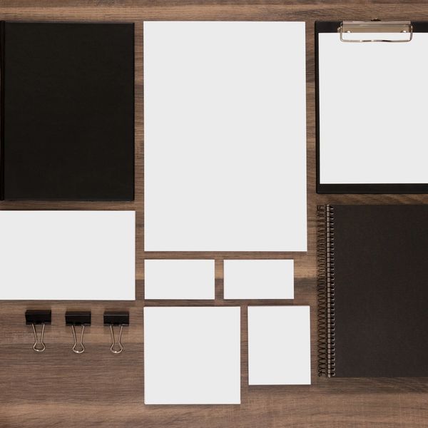 Assorted blank stationery items and office supplies neatly arranged on a wooden surface.