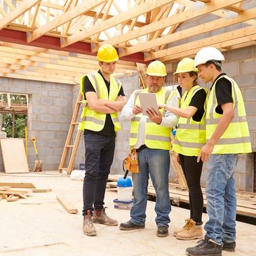 Construction team reviewing plans on a tablet at a building site.