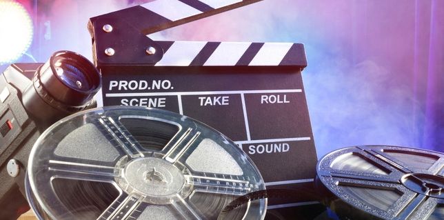 Film reels and clapperboard symbolize movie production and filmmaking.