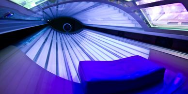 Interior of a tanning bed with blue lighting and a contoured pillow.