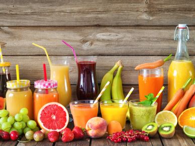Various fresh fruit juices and fruits arranged on a wooden surface.
