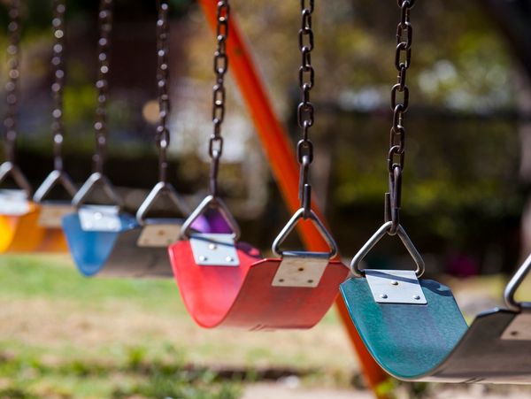 Colorful empty swings hanging in a playground on a sunny day.