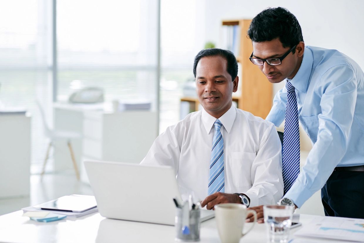 Two businessmen collaborating over a laptop in a modern office.