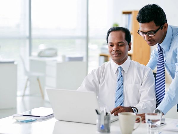 Two businessmen working together on a laptop in an office.