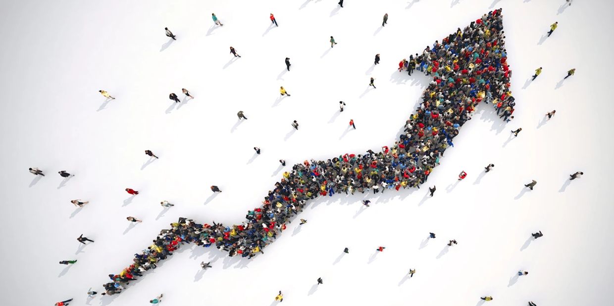 Bird's eye view of people gathered in shape of an arrow trending up.