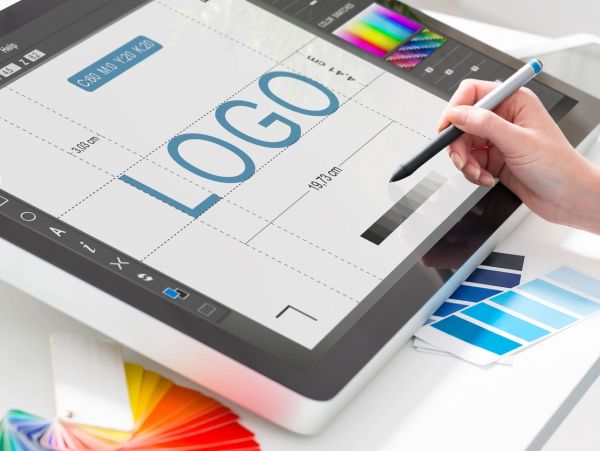 Designer creating a logo on a digital tablet using a stylus.