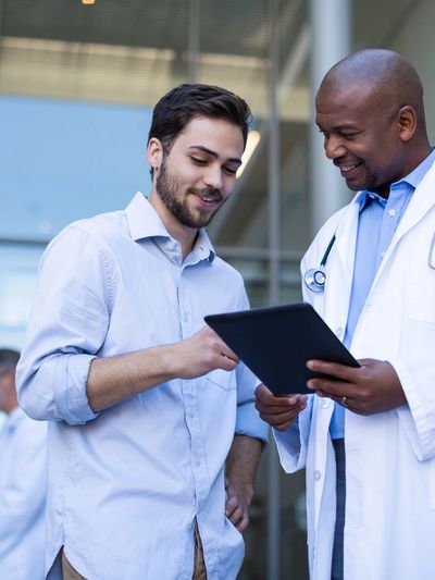 Doctor showing a tablet to a patient outside a clinic.