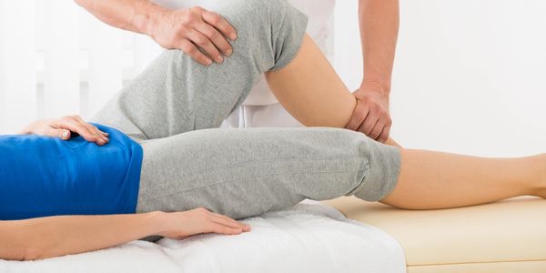 Therapist assisting knee movement during physical therapy.