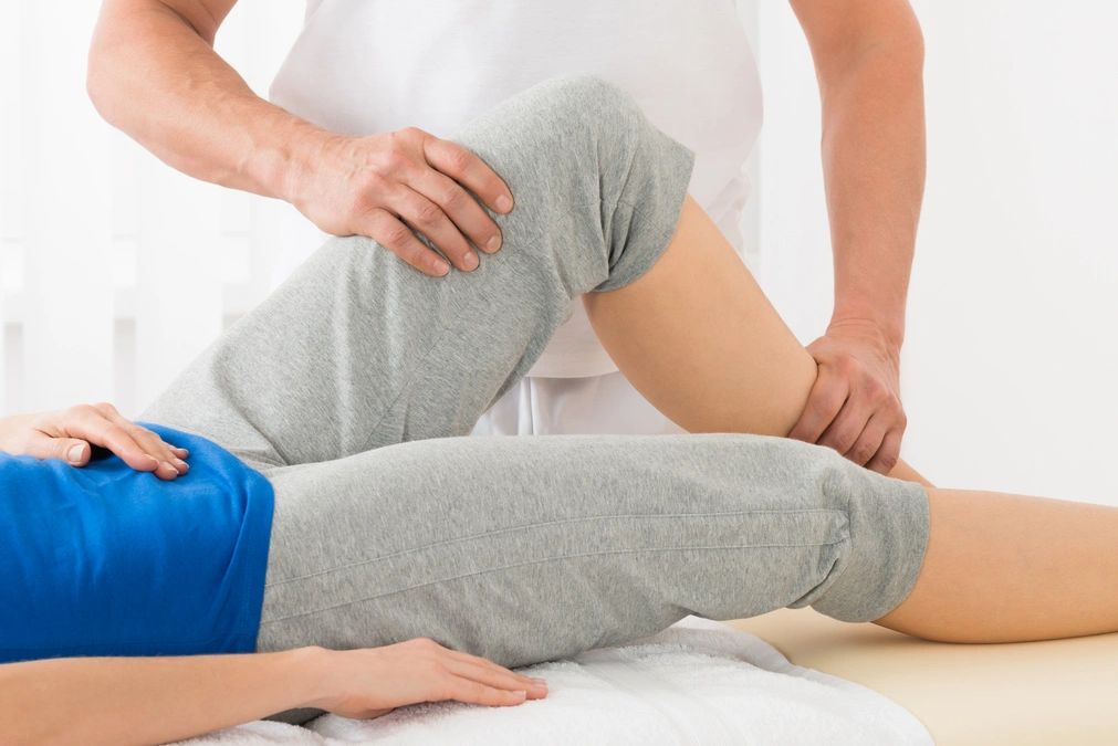 Physical therapist stretching a patient's leg during therapy.