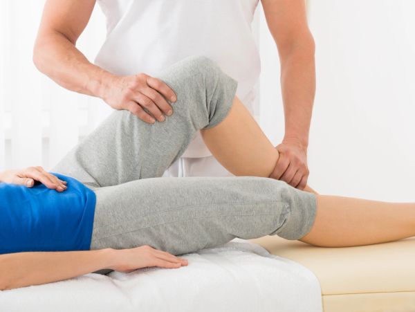 Physical therapist assisting with knee exercise for rehabilitation.