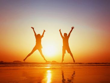 Couple jumping at the beach sunset