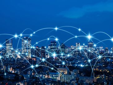 City skyline at night overlaid with glowing wireless network connections.