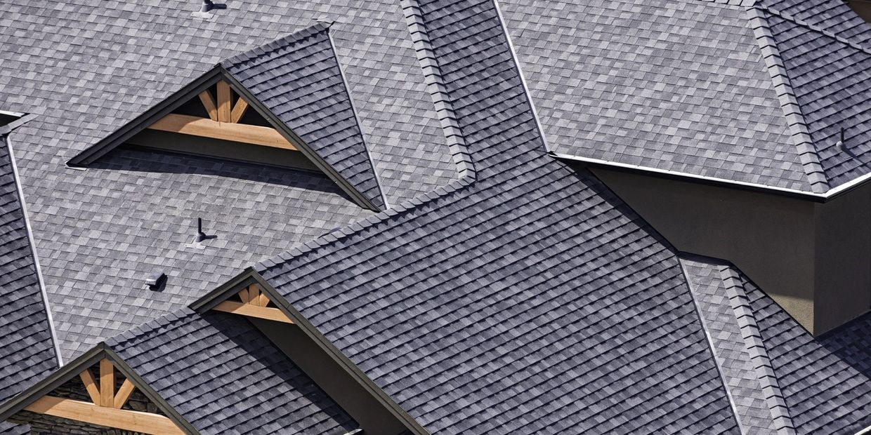 Close-up of a modern house roof with gray shingles and wooden accents.