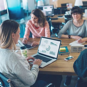 A group of people are gathered around a desk working