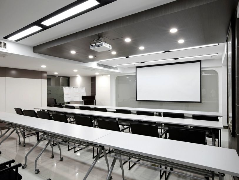 Picture of room with screen to show visuals.  There are also long tables and chairs.