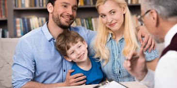 Parents and child looking at therapist who is holding a clipboard 