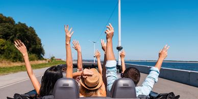 Friends enjoying a road trip with hands raised.
