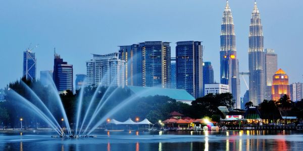City skyline with fountains and illuminated skyscrapers at dusk.