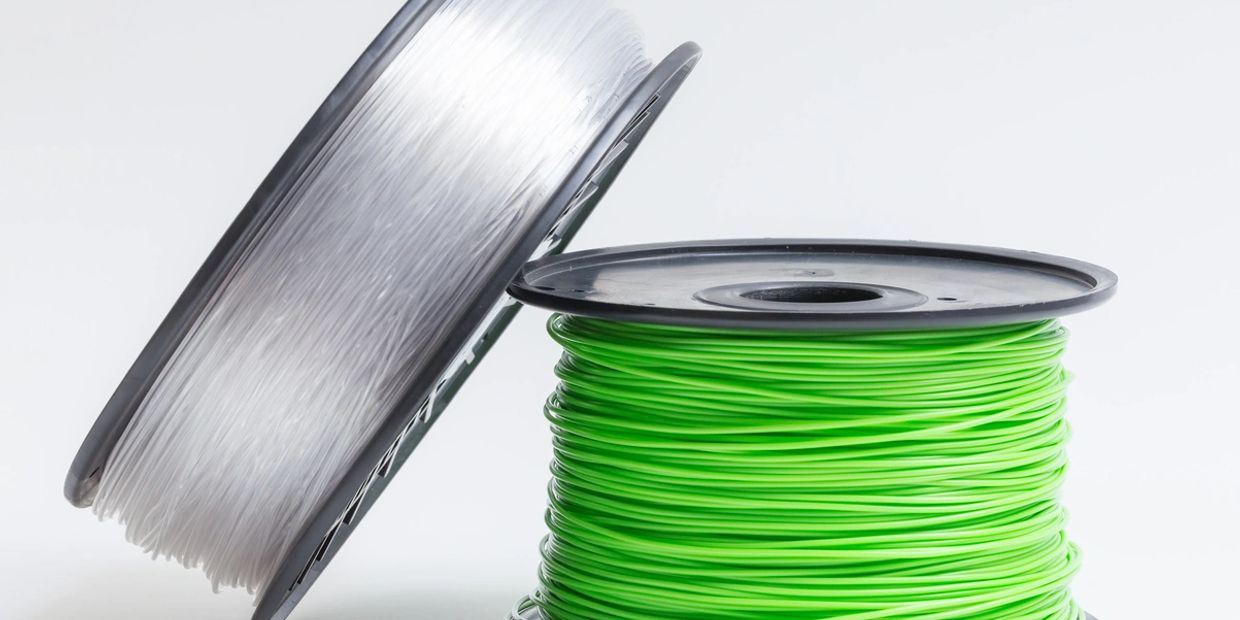 Spools of 3D printer filament in green and transparent colors.
