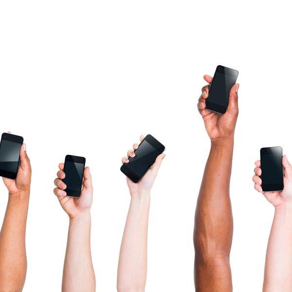 Diverse hands holding up smartphones against a white background.