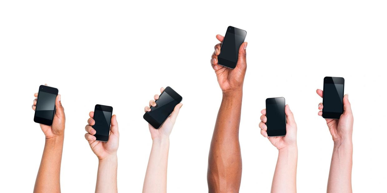 Five hands holding up smartphones against white background.