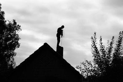 a man sweeping a chimney from the top. 