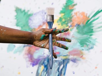  hand holding brush, painting in background 