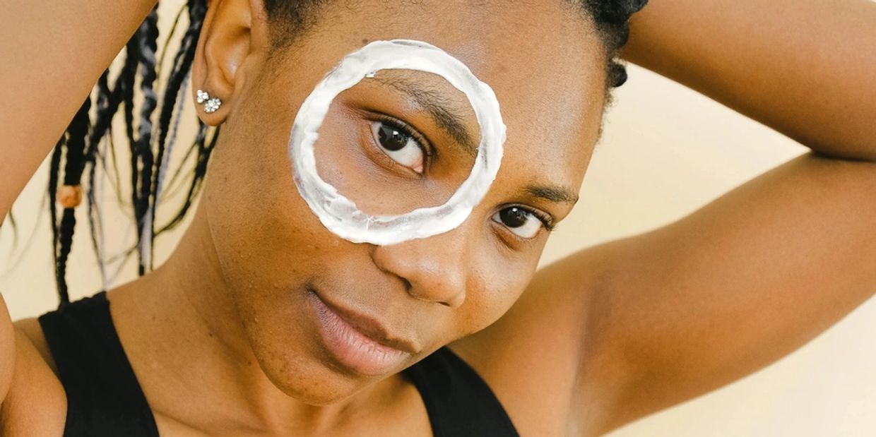 Woman with braided hair and a white cream circle around her eye.