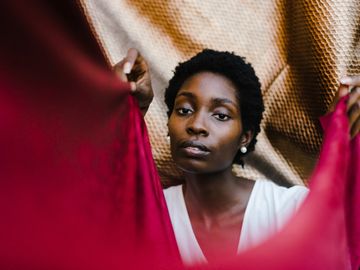 Portrait of a woman framed by red and gold fabrics.