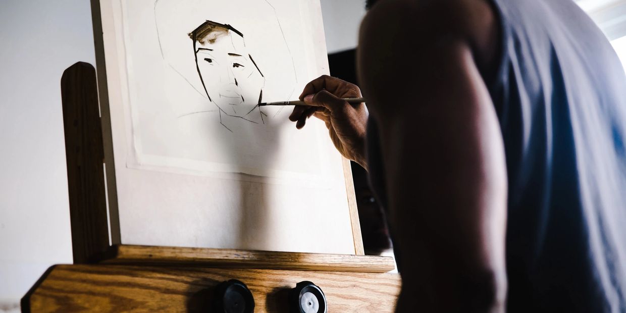 Person painting a portrait sketch on paper.