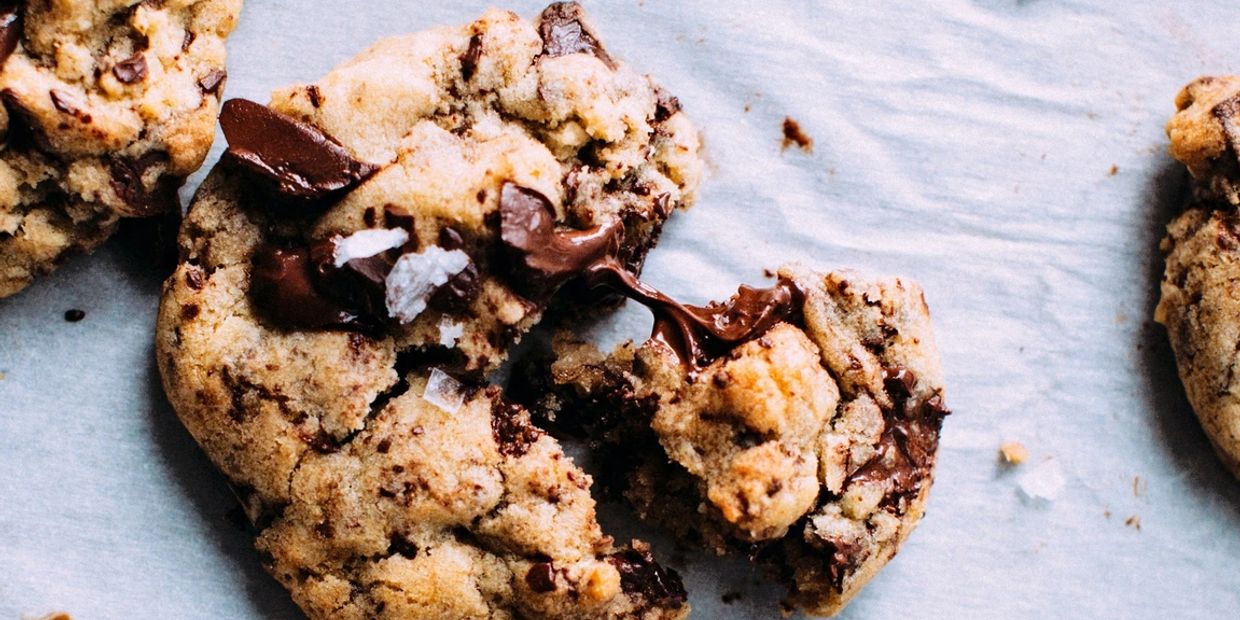 Close-up of chocolate chip cookies, one broken with melted chocolate oozing out.