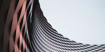 Curved architectural structure with metallic lattice design against the sky.