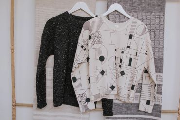 Two sweaters hanging on white hangers.