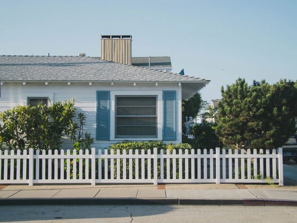 Cozy white house with blue shutters and a white picket fence.