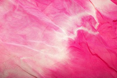 Pink and white tie-dye fabric with soft folds and creases.