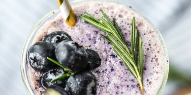 A refreshing blueberry smoothie garnished with fresh berries and rosemary.