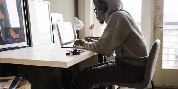 Man working on laptop with headphones on in his home office