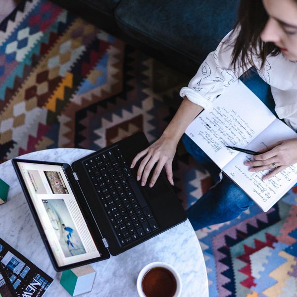 female workin on laptop at coffee table with magazines and coffee mug