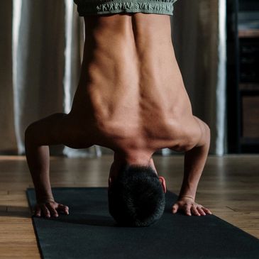 Man performing a headstand yoga pose indoors on a mat.