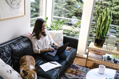 Girl working on her computer next to her dog.