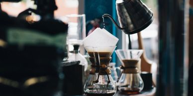 Pour-over coffee brewing in a glass carafe with a paper filter.
