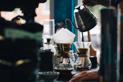 Pour-over coffee brewing with a gooseneck kettle in a cozy café.