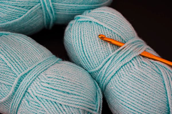 Blue yarn balls with an orange crochet hook.
